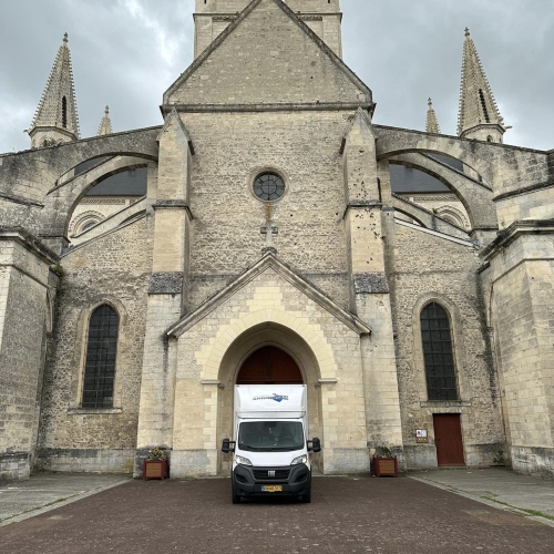 Flyttebil parkeret foran en stor kirke i udlandet under en international flytning. Sikker transport af ejendele ved flytning til udlandet.