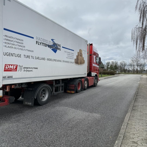 Flyttelastbil parkeret langs vej under erhvervsflytning. Haderslev og Vojens flytteforretning klar til transport for erhvervskunder.