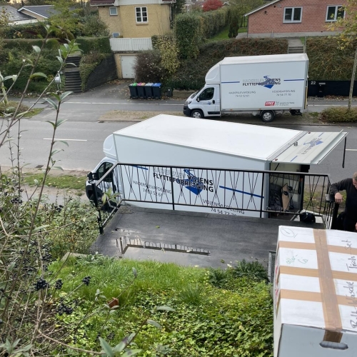 To flyttebiler parkeret foran et hus under privatflytning. Flyttefirma sikrer effektiv og sikker flytning af ejendele