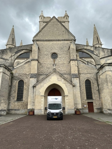 Flyttebil parkeret foran en stor kirke i udlandet under en international flytning. Sikker transport af ejendele ved flytning til udlandet. 