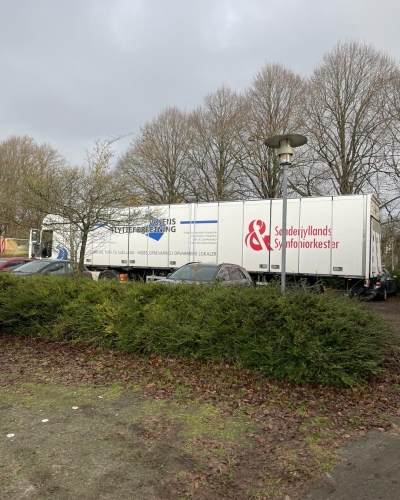 Flyttelastbil parkeret ved flere biler, klar til levering. Effektiv håndtering af flytning fra Haderslev og Vojens flytteforretning. 