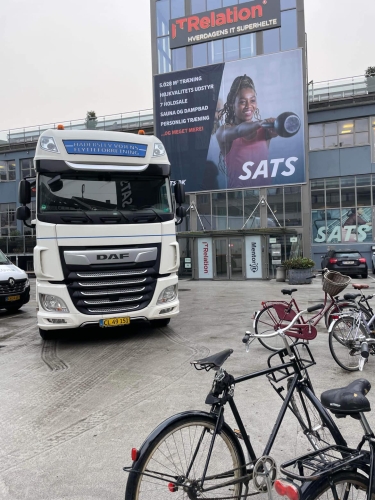 Flyttelastbil foran SATS-fitnesscenter under en erhvervsflytning. Effektiv flytning af udstyr for erhvervskunde. 